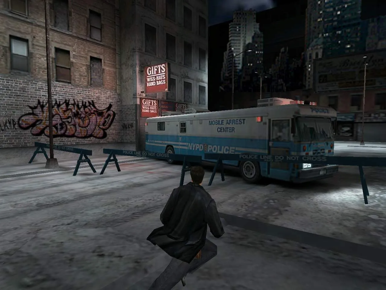 Max Payne — Max runs down a snow-covered New York street at night, past police barricades and an NYPD mobile arrest bus